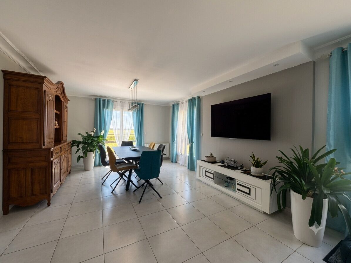 Een moderne woonkamer met een eethoek, een flatscreen televisie aan de muur en een grote houten kast.