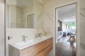 Ein modernes Badezimmer mit einem großen Spiegel, zwei Waschbecken und Holzschränken.