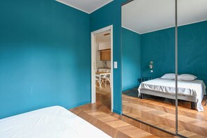 Ein Zimmer mit Türkiswänden, einer Schranktür mit Spiegel und einem Holzboden.