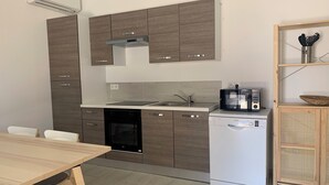 Ett modernt kök med diskmaskin, mikrovågsugn och ett matbord i trä.