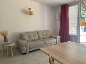 Ein modernes Wohnzimmer mit einem beigefarbenen Sofa, einem kleinen runden Tisch und einem Holzessttisch.