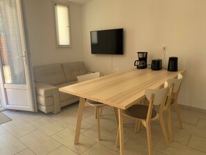 Ein modernes Wohnzimmer mit einem Holzesstisch, einem beigefarbenen Sofa und einem an der Wand montierten Flachbildfernseher.