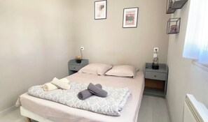 A bedroom with a bed, two bedside tables, a window, and two framed pictures on the wall. - Spacious Family Holiday Home with Pool near Uzès – Sleeps 4 (Saint-Siffret)