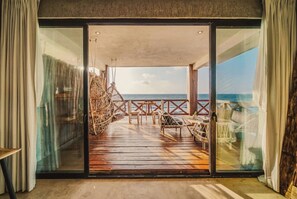 A deck with a glass door leading to a balcony overlooking the sea.