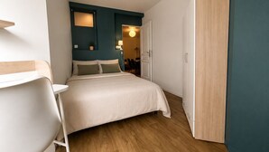 Une chambre à coucher avec un lit, un bureau, une chaise et une armoire.