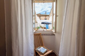 A narrow window with white curtains, a wooden chair, and a book titled 'Chenin de Gout' on the chair. - L'Escapade Minervoise, the ideal place to stay with family or friends (Laure-Minervois)