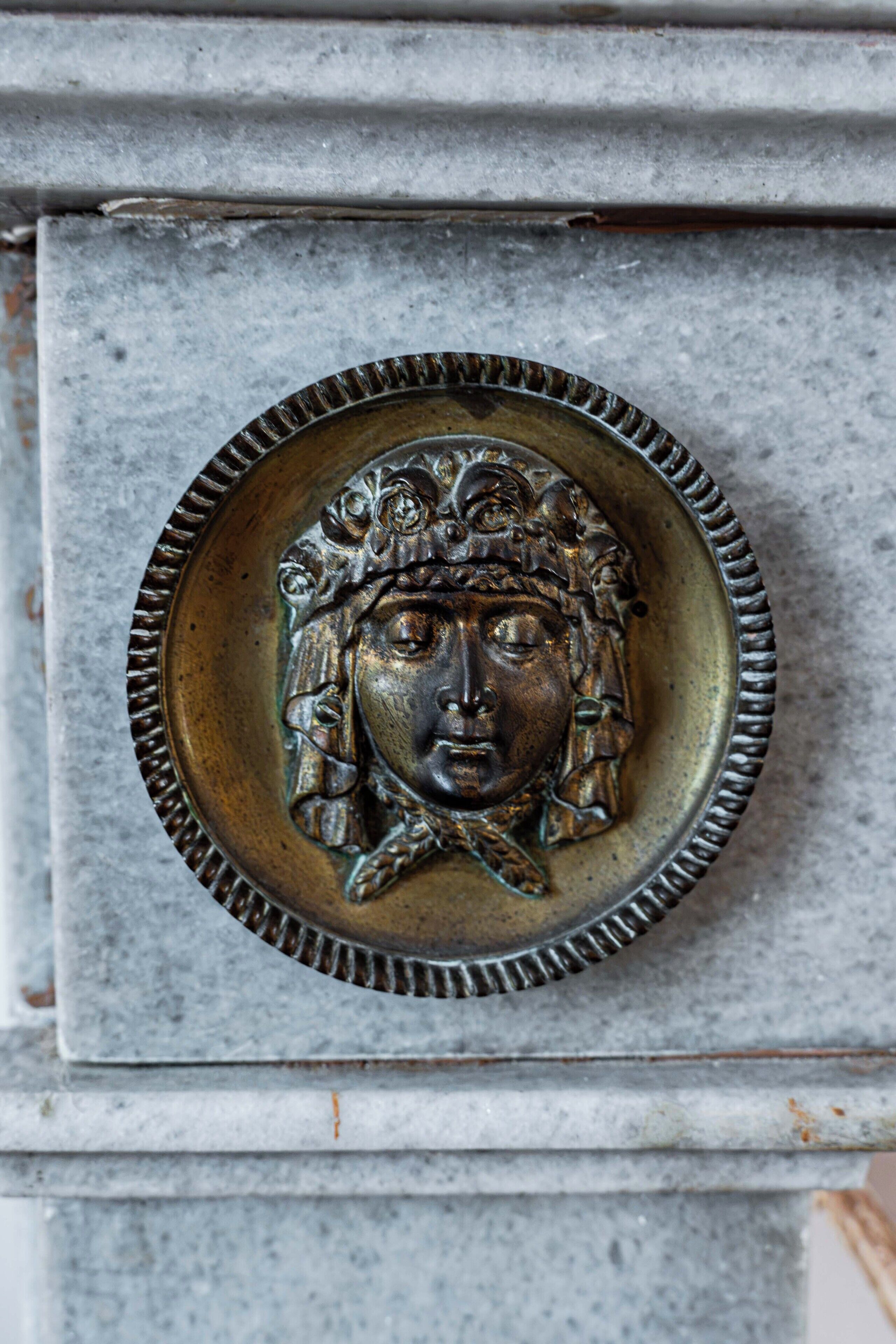 Una placa metálica detallada con un diseño circular, posiblemente un adorno en la fachada de un edificio.
