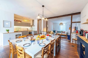 A modern kitchen with a dining area, wooden flooring, and a visible kitchen island. - L'Escapade Minervoise, perfect for families or friends   (Laure-Minervois)