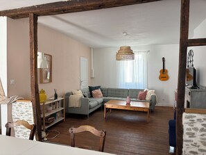 Ett vardagsrum med en soffa, ett soffbord, en gitarr och en tv.