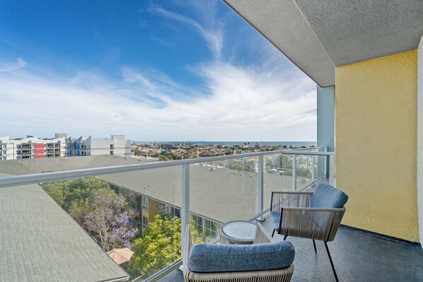A balcony with a view of the city, a chair, and a small table.