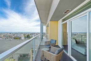 A balcony with a view of a cityscape, a glass door, and a small table with chairs.