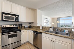 A modern kitchen with stainless steel appliances, a granite countertop, and a window offering a city view. - Sunset Pearl' Full Ocean Views Pool Gym & Parking Available (Marina del Rey)