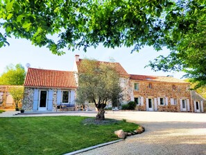 A stone building with a red-tiled roof, a tree in the foreground, and a gravel driveway. - Charming farmhouse & Open spaces (Les Cerqueux)