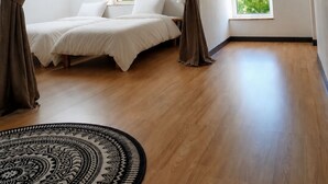 Un dormitorio con cama, cortinas, tragaluz, ventana, alfombra redonda y lámpara tejida.