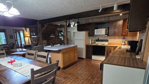 A spacious kitchen with a dining area, wooden cabinets, and a brick floor. - ~ Riverfront, Hot Tub, Mountain Views, 8 Beds ~ (Cascade)