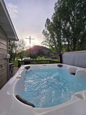 A hot tub in a backyard with a wooden deck, a grill, and a picnic table. - ~ Riverfront, Hot Tub, Mountain Views, 8 Beds ~ (Cascade)