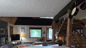 A spacious living area with a large wooden cabinet, a fireplace, and a stone fireplace surround. - ~ Riverfront, Hot Tub, Mountain Views, 8 Beds ~ (Cascade)