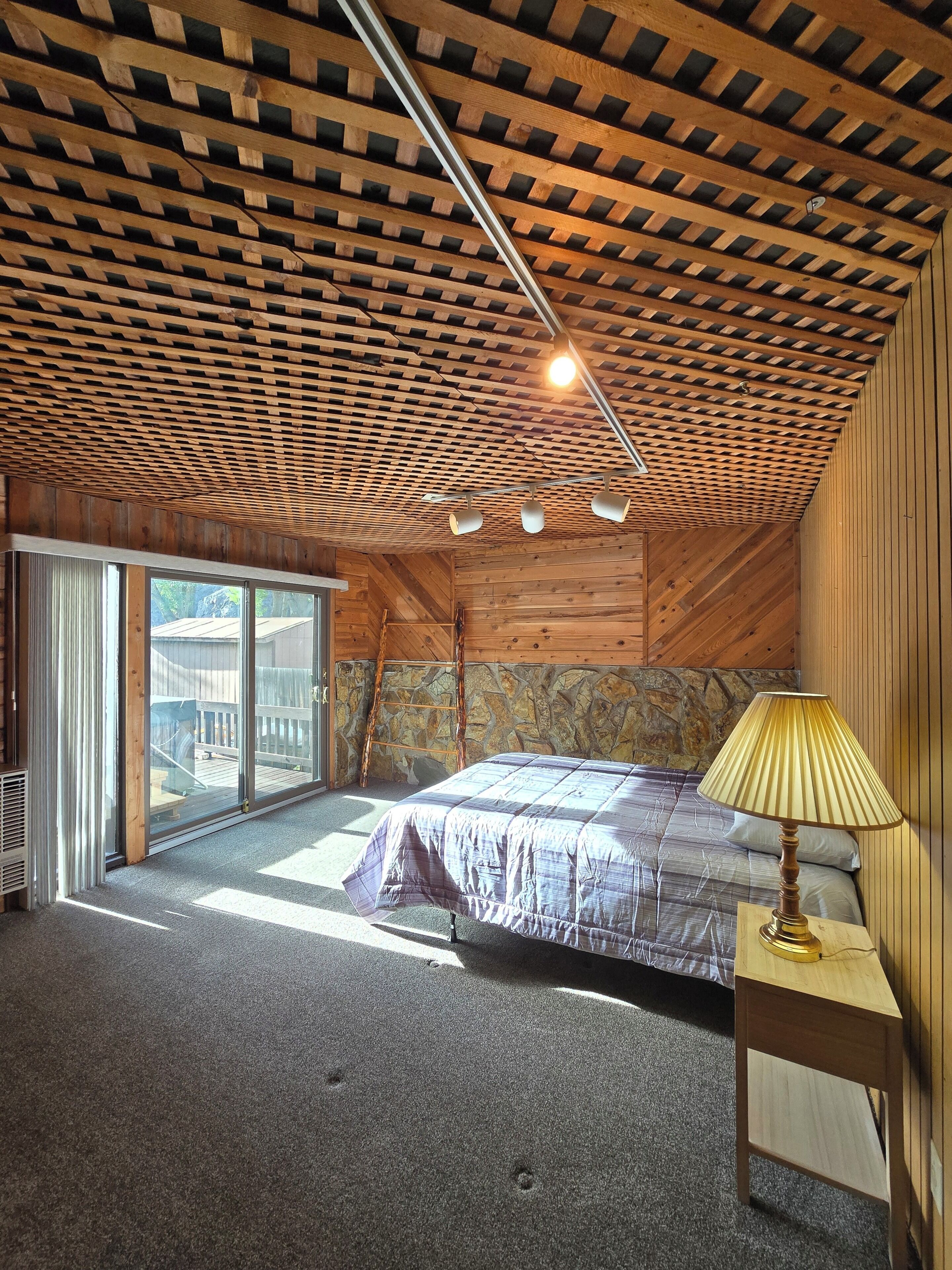 Ein Schlafzimmer mit schrägem Dach, einem Bett, einem Nachttisch und einem Fenster.