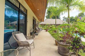 A covered outdoor area with wicker chairs, potted plants, and a thatched-roof structure. - Walk to Beach, 4 BR/ 4BA Villa, Pool Garden Rancho (Playa Grande)