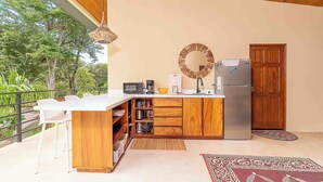 Een moderne keuken met een houten eiland, witte barstoelen, een ingebouwde magnetron en een koelkast.
