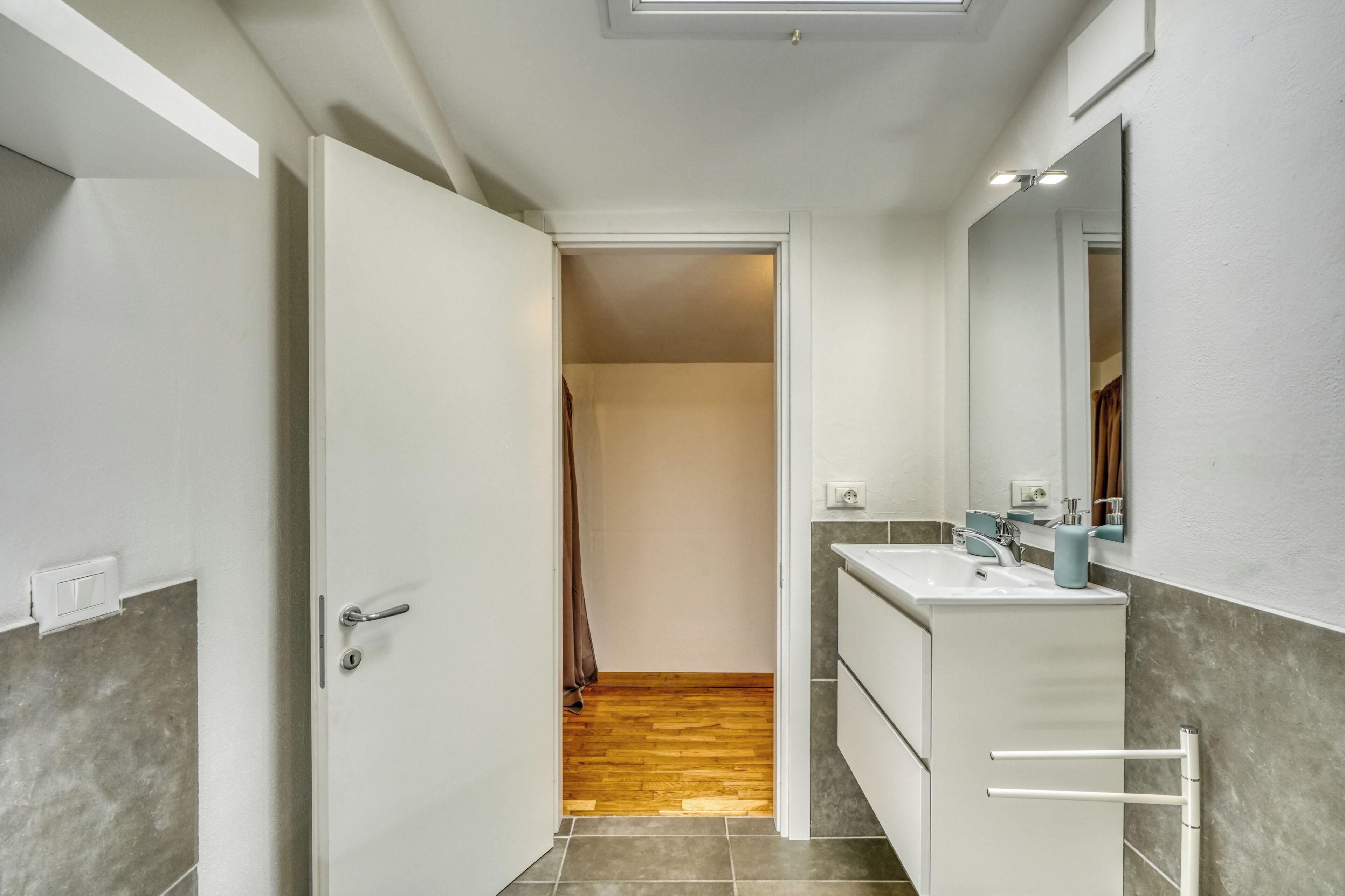A modern bathroom with a white vanity, a mirror, and a shower area.