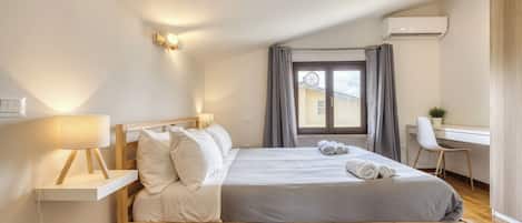 Ein modernes Schlafzimmer mit einem hölzernen Bett, einer Nachttischlampe und einem Schreibtisch mit Stuhl.