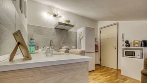 A compact kitchen with a white countertop, a built-in microwave, and a wooden floor. - Il Rifugio di Manu (Lucca)