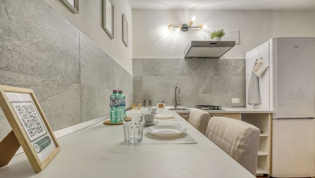 A modern kitchen with a marble backsplash, a built-in stove, and a refrigerator. - Il Rifugio di Manu (Lucca)