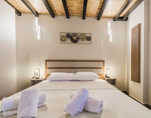 Ein Hotelzimmer mit einem Bett, zwei Nachttischen, einer Kopfteil und einem Wandbild sowie einer Wanddekoration aus Holzleisten.