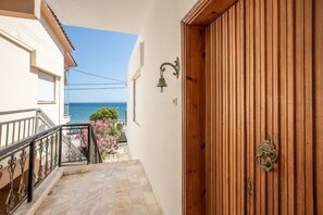 A corridor with a wooden door, a metal bell, and a view of the sea. - 10 Steps to the beach by Rentals Pro - Kalives Halkidiki (Kalyves Polygyrou)