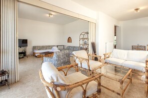 A spacious living area with a large mirror, a television, and a bed with patterned bedding.
