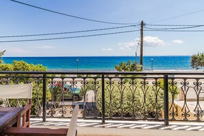 A balcony with a view of the sea, a car, and a building in the background. - 10 Steps to the beach by Rentals Pro - Kalives Halkidiki (Kalyves Polygyrou)