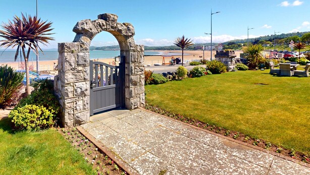 Un arco in pietra che conduce a una zona erbosa con vista sulla spiaggia e sull'oceano.