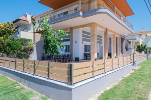 Ein modernes, zweistöckiges Haus mit Balkon, Sitzgelegenheit im Freien und einem gepflegten Garten.
