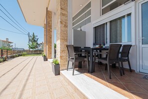 Eine Terrasse im Freien mit Esstisch, Stühlen, Steinpfeilern und Blumentöpfen.