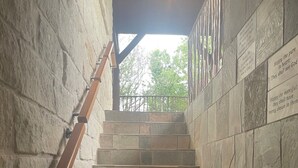 A stone staircase with wooden handrails leading to a covered area with a view of trees. - The Upper Room | 360° Patio Views & Elevated Hill Country Escape (Buda)