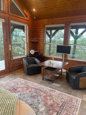 Ein Holzblockbau-Innenraum mit einer Couch, einem Tisch und einem großen Fenster.