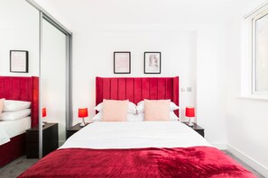 Ein Hotelzimmer mit einem großen Bett, einem roten Kopfteil, einem Spiegel und zwei Nachttischen mit Lampen.
