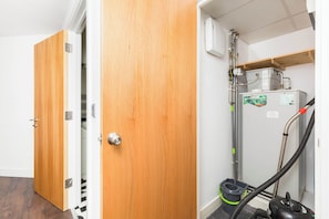 Ein Zimmer mit Holztür, Staubsauger und weißer Wand mit Lüftung.