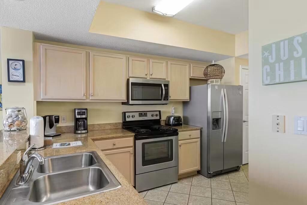 A kitchen with a stainless steel sink, a microwave, a stove, a refrigerator, and a toaster.