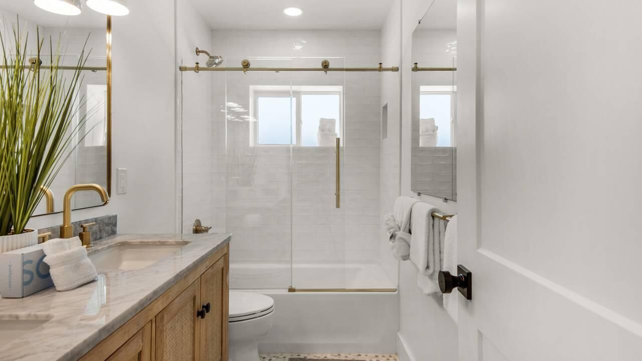 A modern bathroom with a glass-enclosed shower, a marble sink, and a large mirror.
