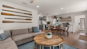 Una cocina moderna con armarios blancos, un refrigerador de acero inoxidable y un comedor con sillas de madera y una mesa redonda.