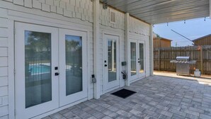 A covered patio with a pool, sliding glass doors, and a barbecue grill. - A Salty Cru (Panama City Beach)