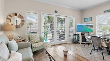 Uma sala de estar com sofá, mesa de centro, TV e área de refeições com cadeiras.