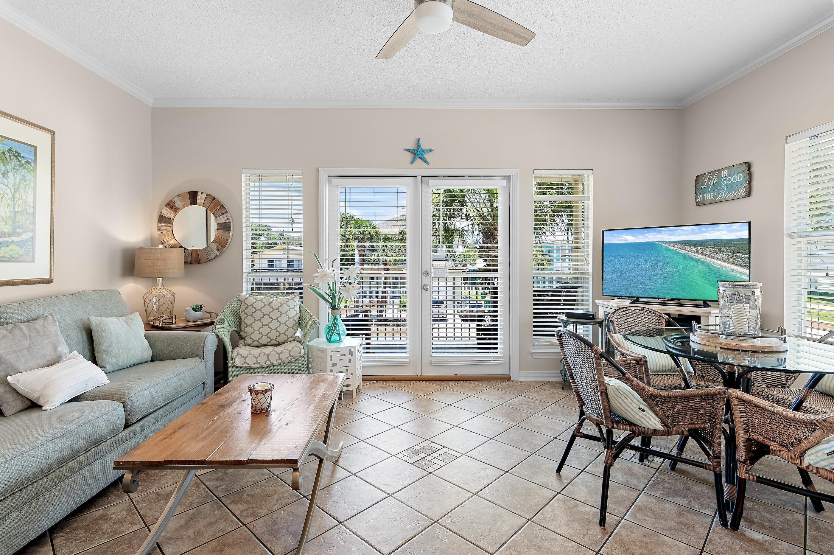 A living room with a sofa, coffee table, wicker chairs, a TV, and a star decoration on the wall.
