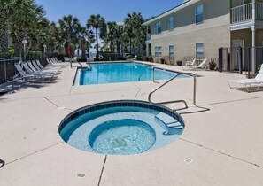 Ein Pool mit Liegestühlen, einem Whirlpool und einem Gebäude mit Balkonen.