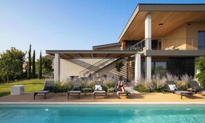 Une maison moderne dotée d’une piscine, d’un espace salon extérieur et d’un patio couvert.