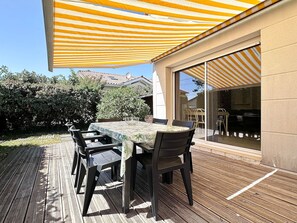An outdoor patio with a striped awning, a table with chairs, and a glass door leading to an interior space. - Fronton 5 - 2-bedroom ground-floor apartment, 900 meters from the ocean (Mimizan)