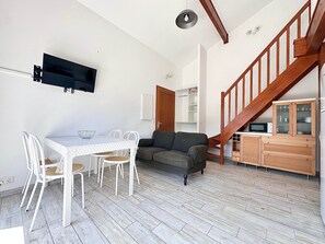 Ein kompakter Wohnraum mit Esstisch, Stühlen, einer Couch, einer Treppe und integrierten Schränken.