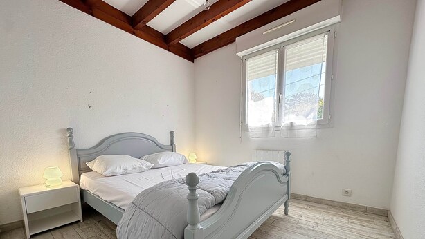 A bedroom with a bed, nightstands, a window, and a wooden floor. - Fronton 5 - 2-bedroom ground-floor apartment, 900 meters from the ocean (Mimizan)